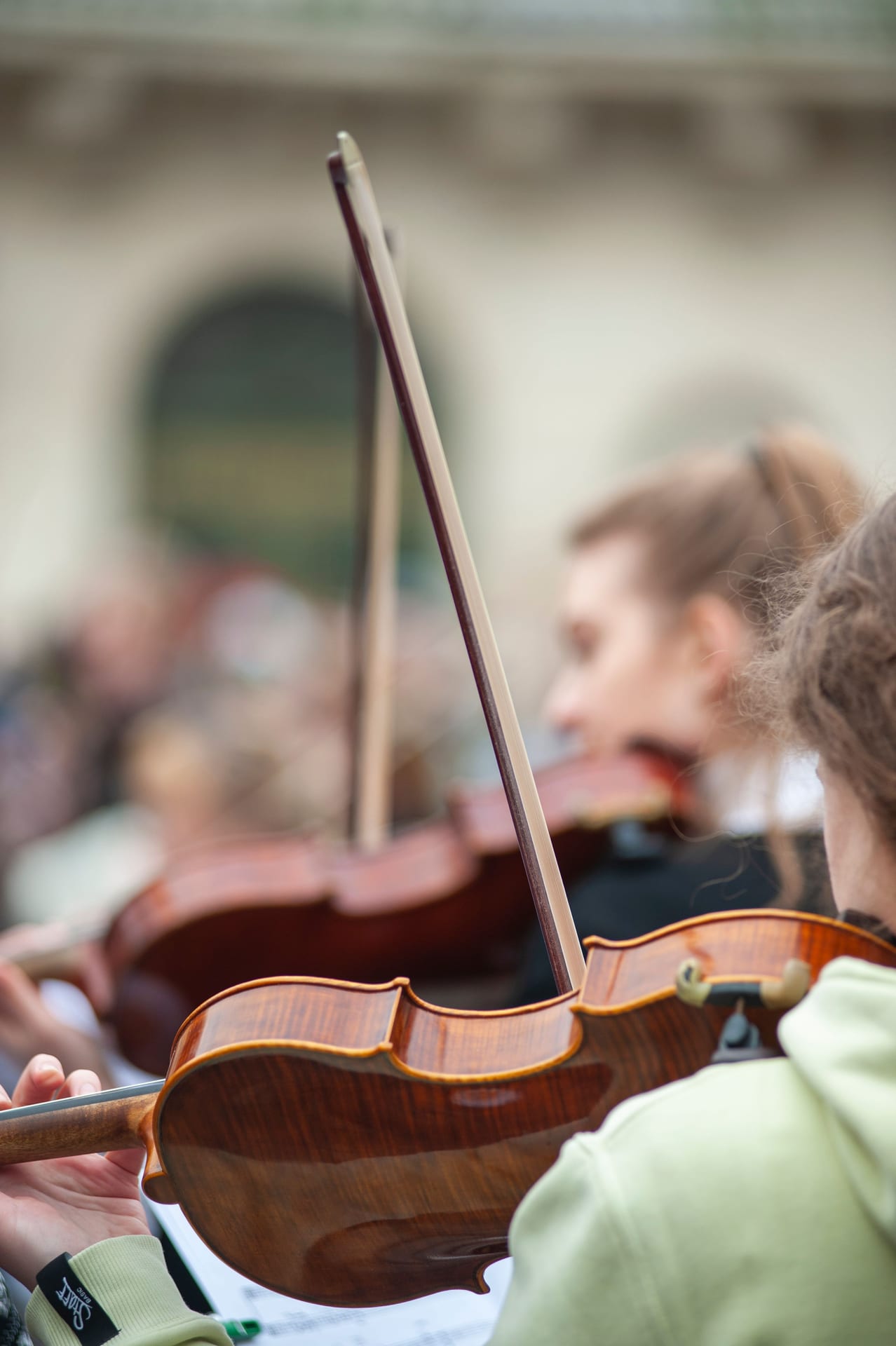 A close-up view of violinists playing in an outdoor performance, showcasing musical passion.