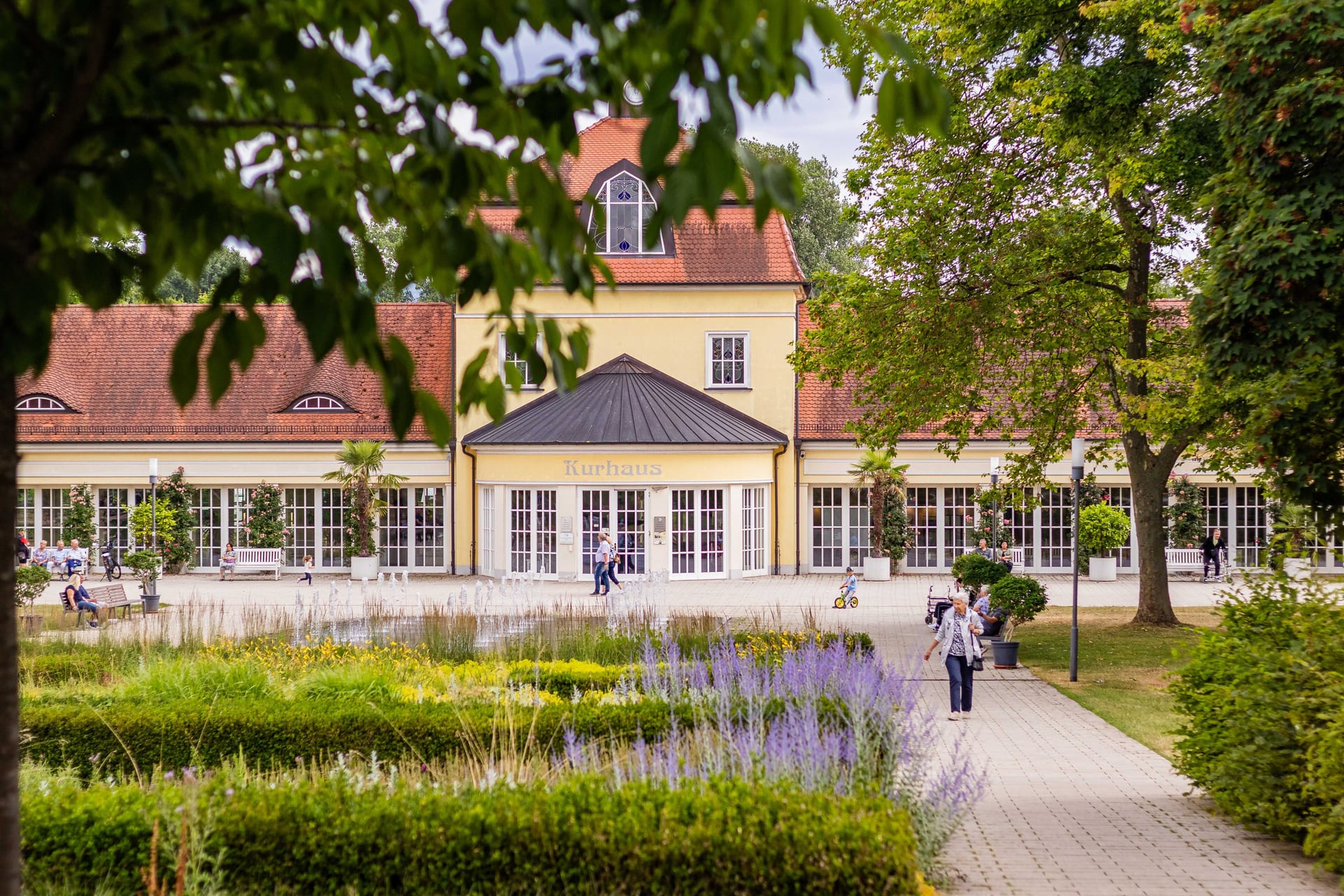 Scenic view of a Kurhaus building surrounded by vibrant gardens and walking paths.