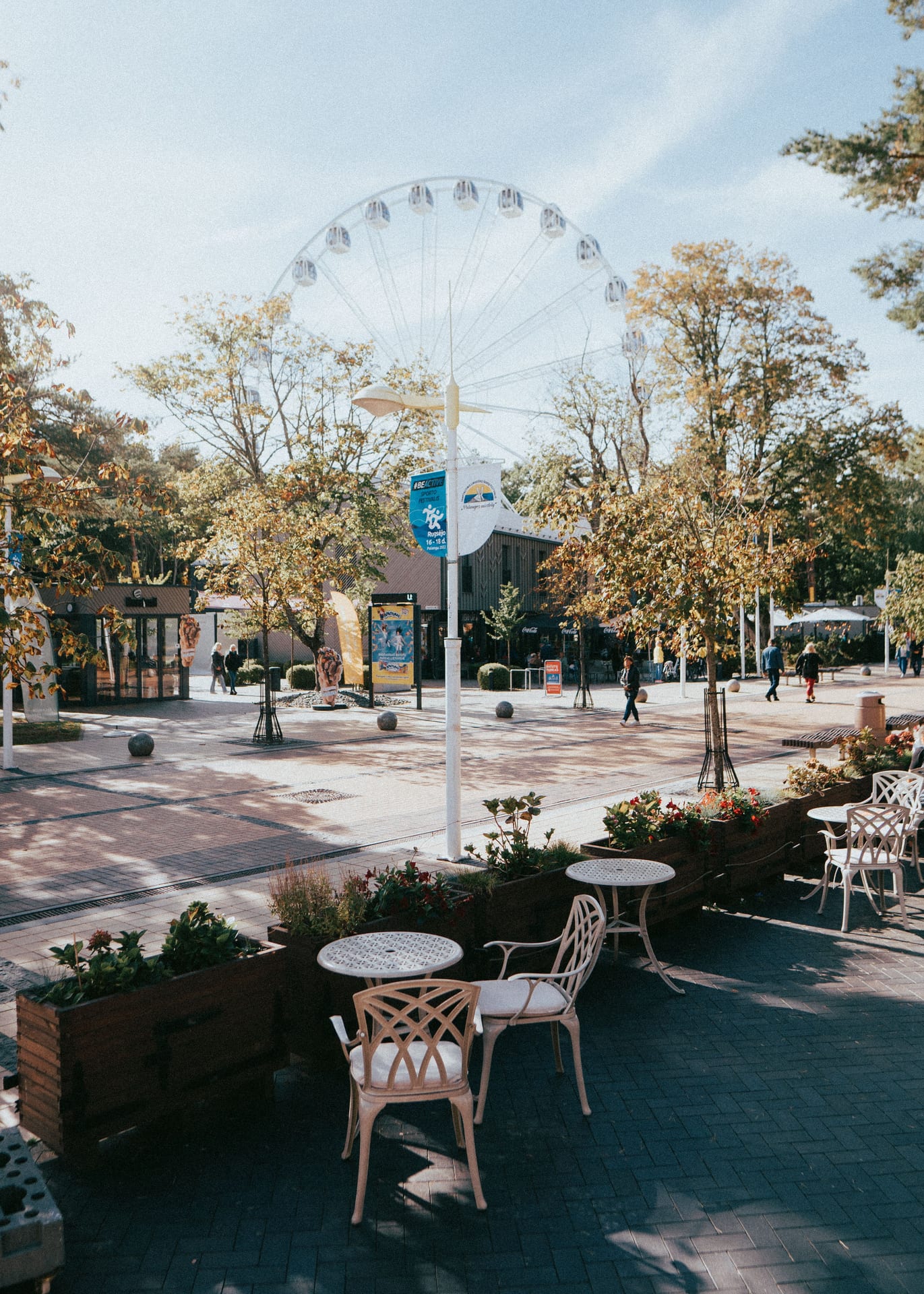 Scenic view of Palanga's lively town square featuring a Ferris wheel and outdoor café setting.